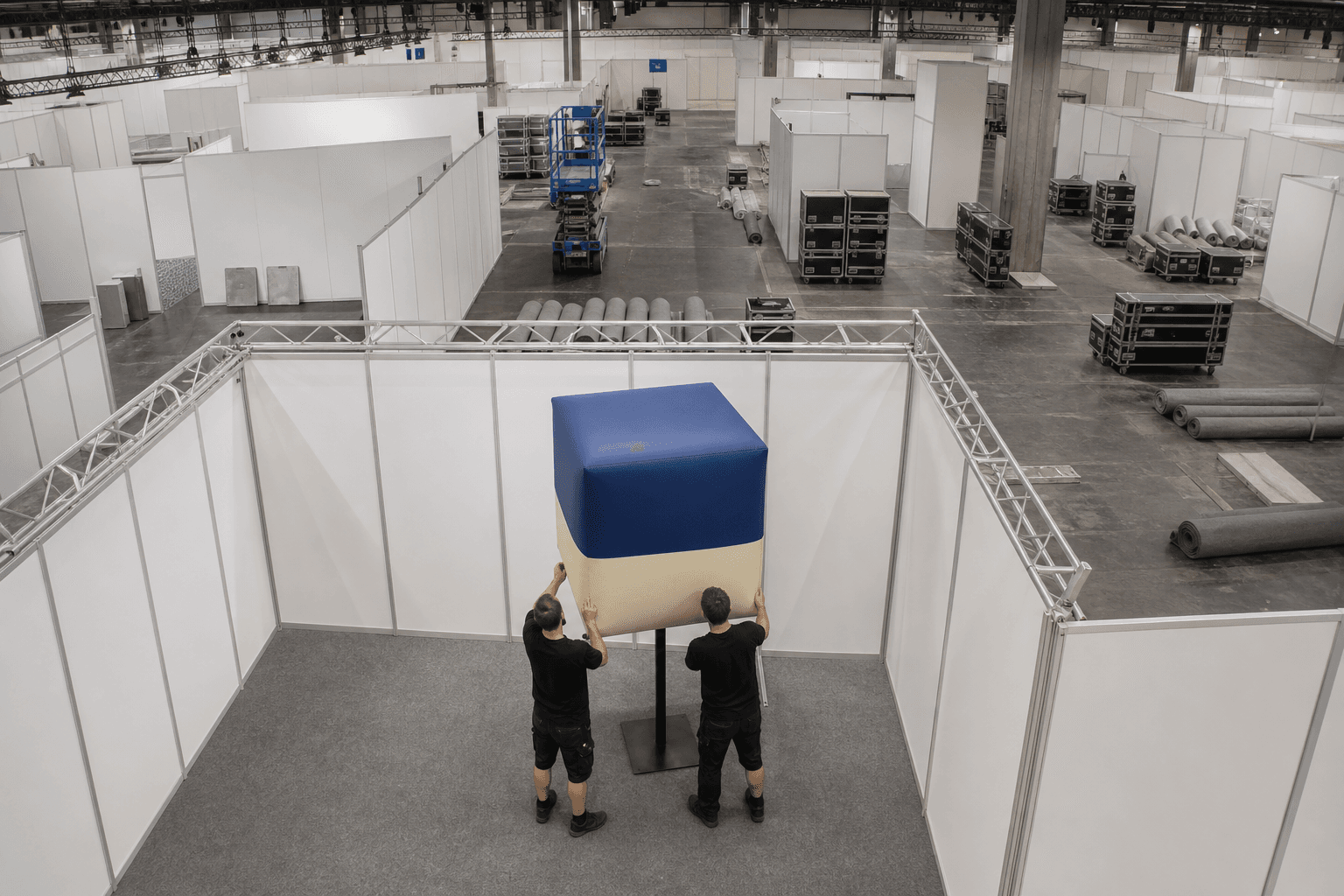 Blue and cream inflatable cube being positioned in a trade fair hall