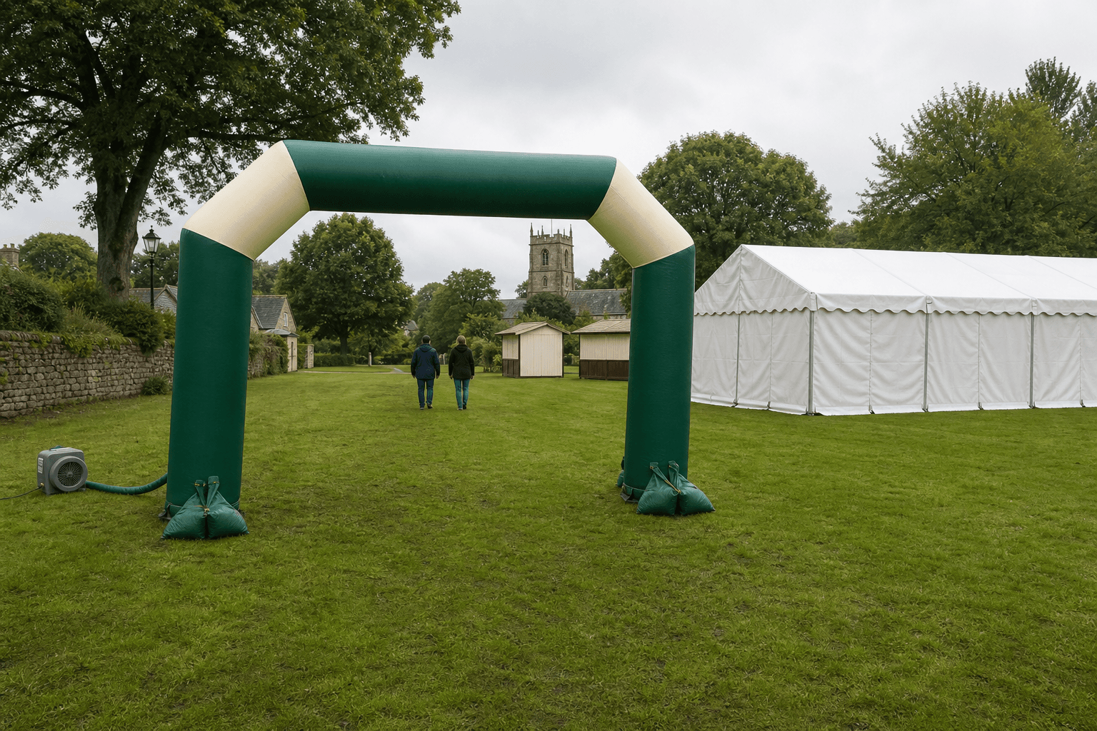 Green and cream inflatable arch and white marquee on a village green