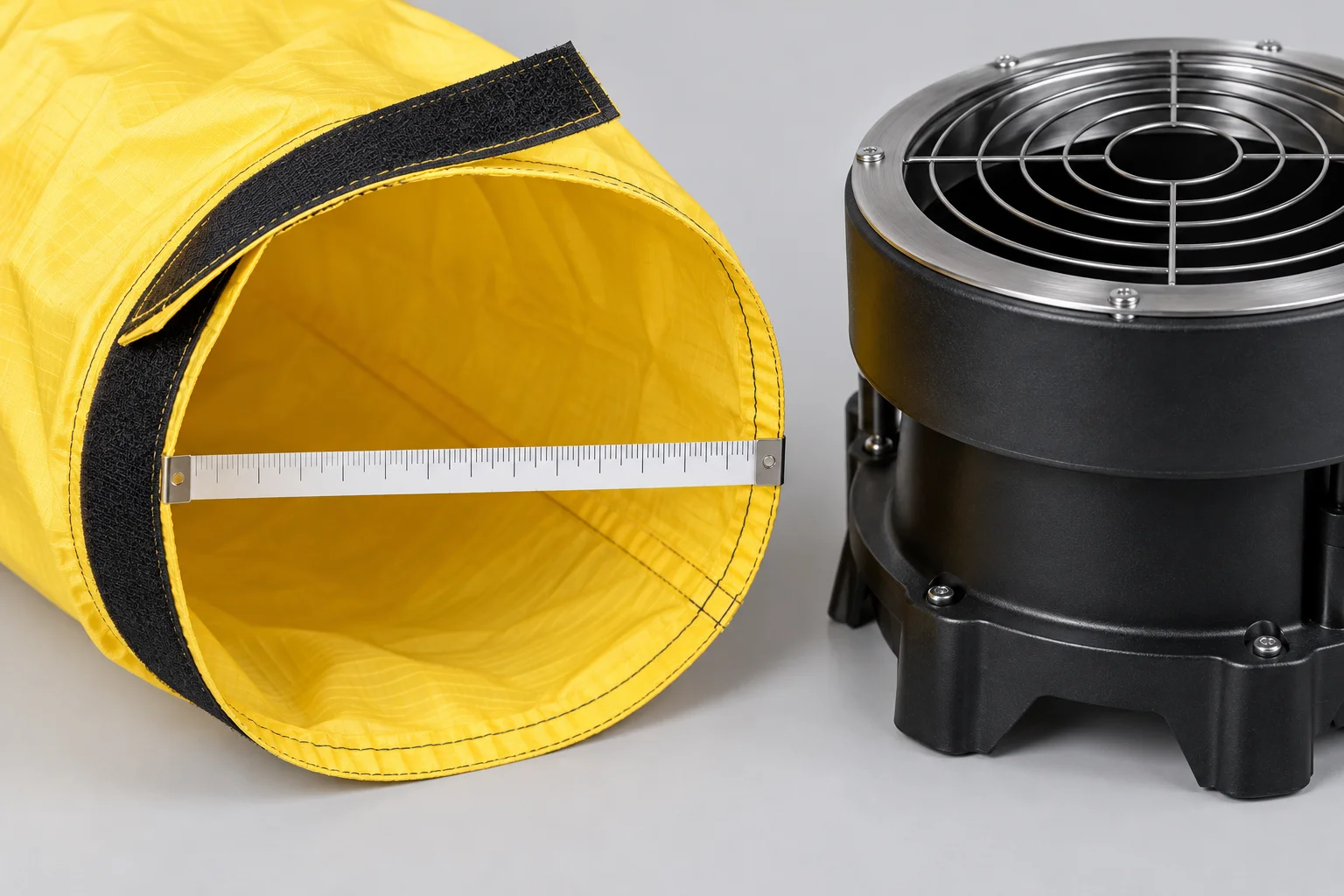 Close-up of a yellow fabric tube base, hook-and-loop fastening strip and measuring tape beside a blower outlet.