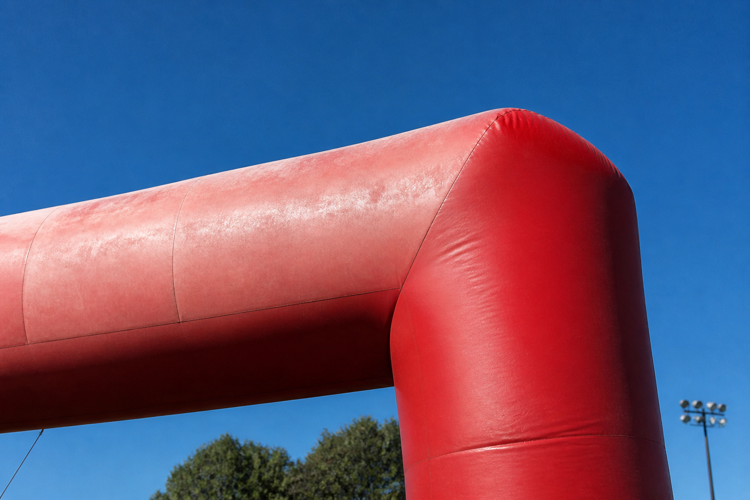 Upper surface of an outdoor inflatable in bright sunlight showing a faded panel next to a shaded one