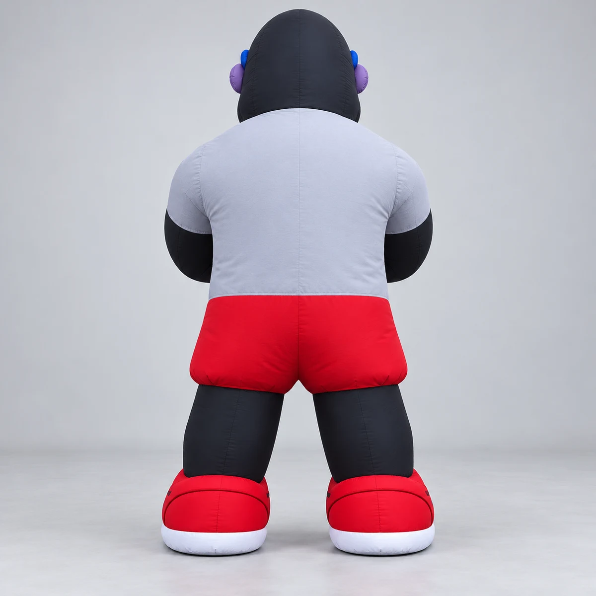 Rear concept view of gorilla mascot with gray-white short-sleeve T-shirt, red shorts and red-and-white sneakers